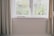 A bright living room with a pleated screen mesh installed on a large window, showcasing a view of a garden.
