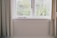 A bright living room with pleated insect screens elegantly installed on large windows.