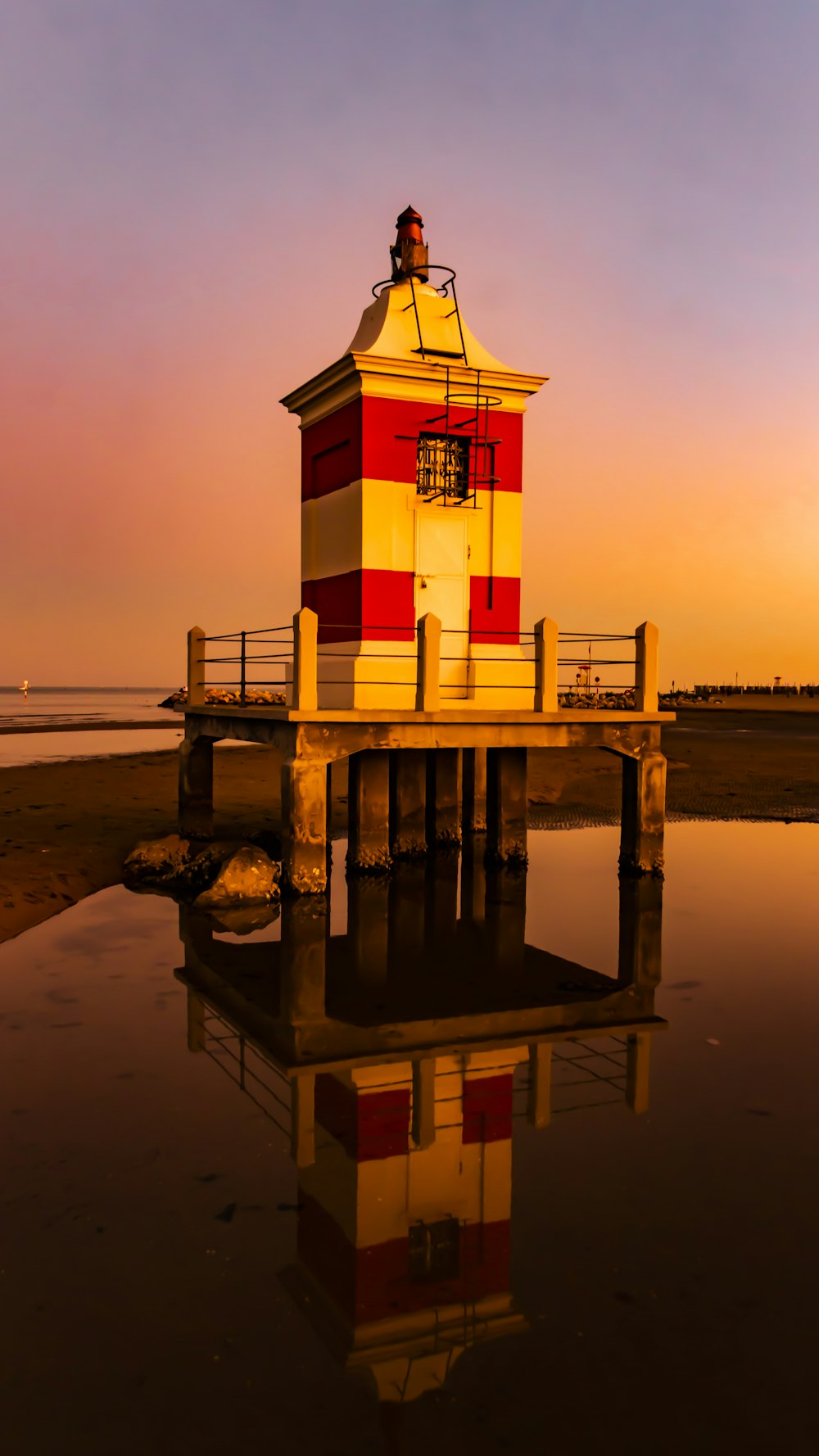 a red and white lighthouse sitting on top of a pier