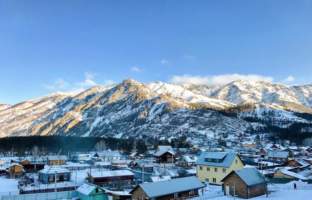 a snow covered mountain range with houses in the foreground