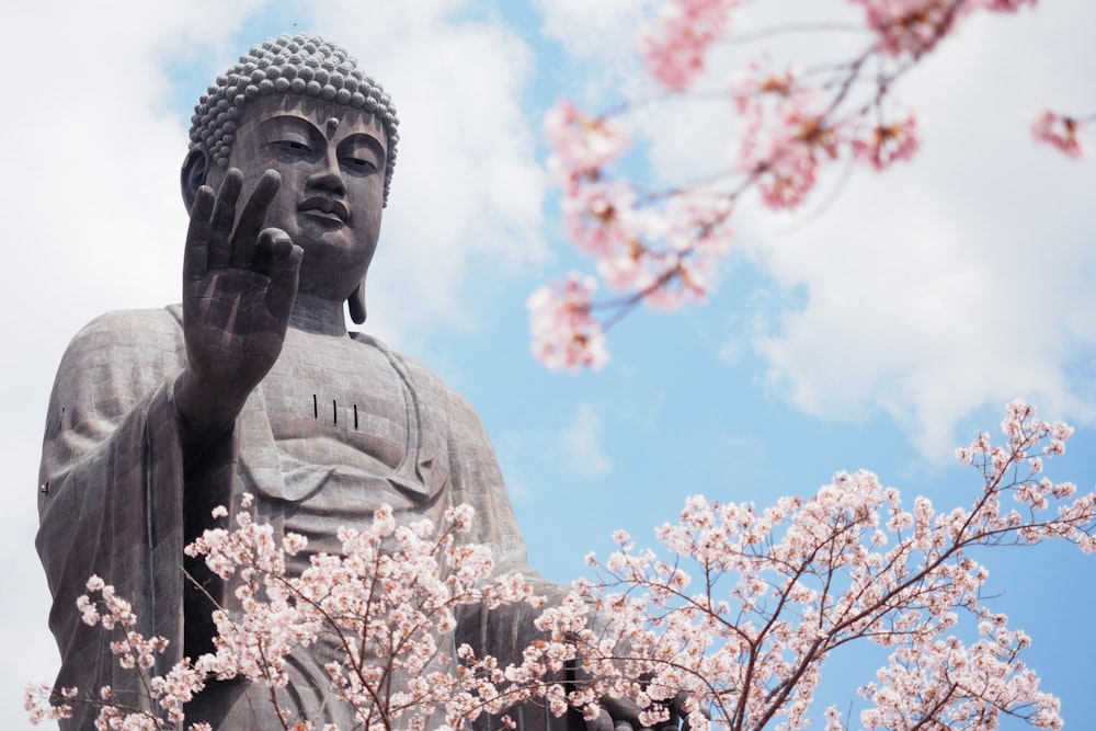 a statue of a buddha surrounded by pink flowers