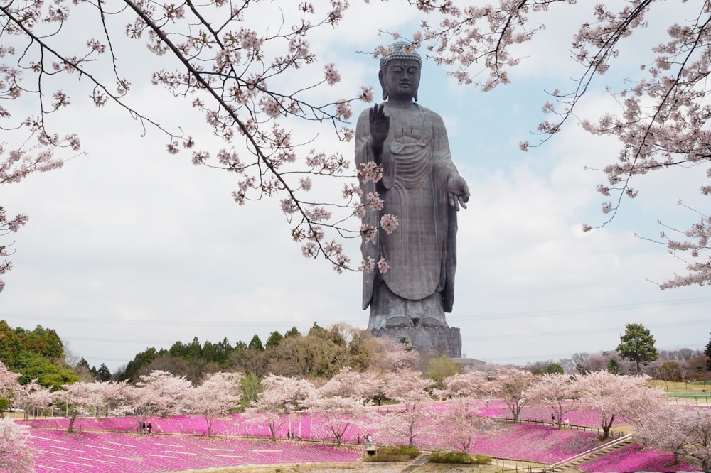 a large statue of buddha surrounded by pink flowers