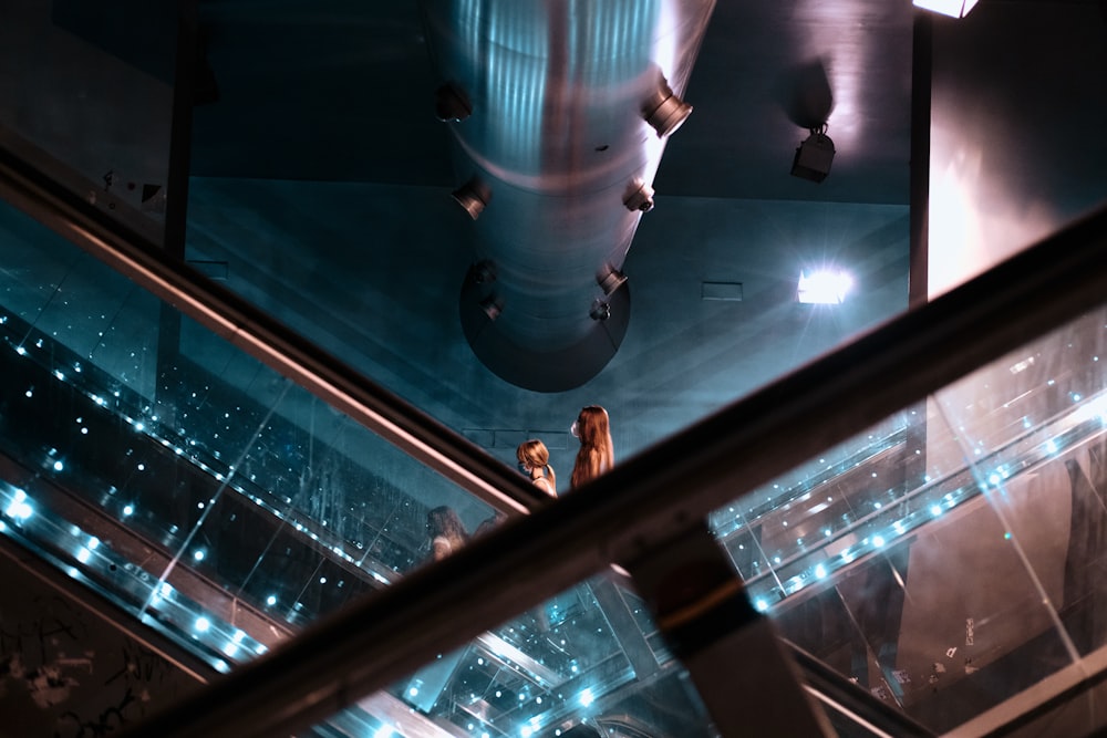 a couple of people standing on top of an escalator