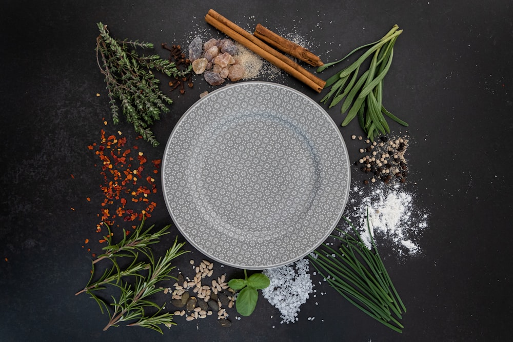 a plate surrounded by spices and herbs