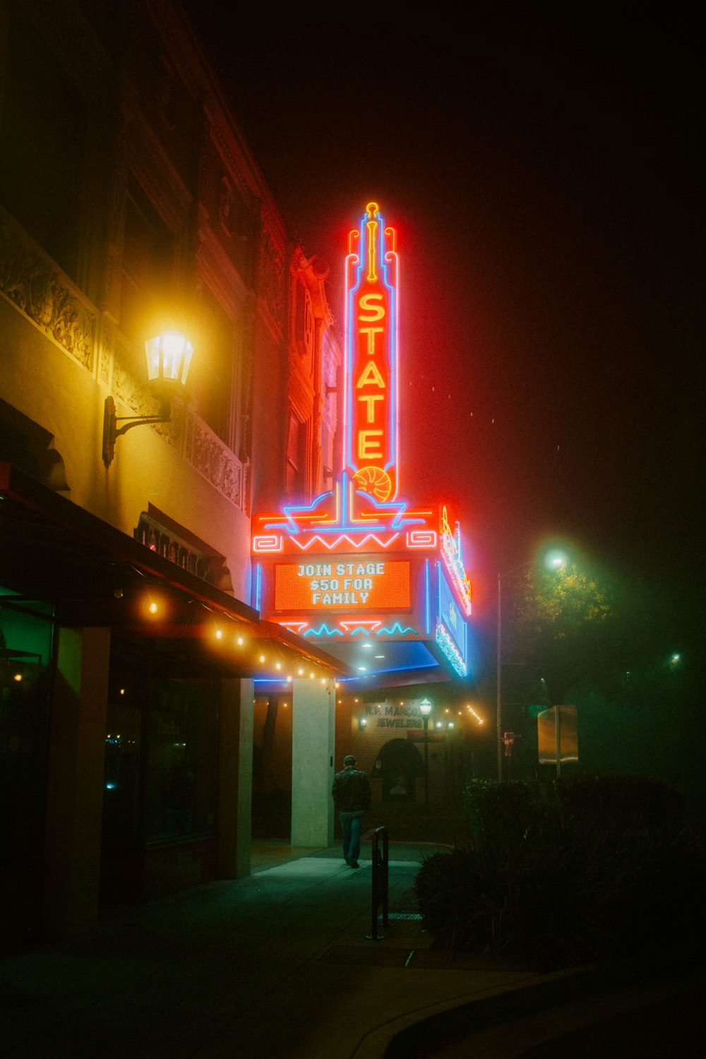 a theater sign lit up at night on a city street