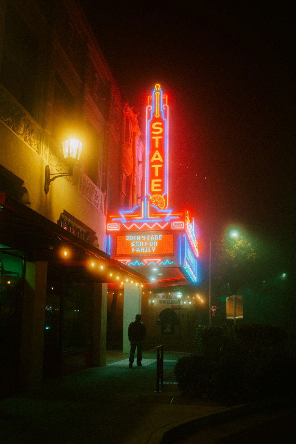 a man standing in front of a theater at night