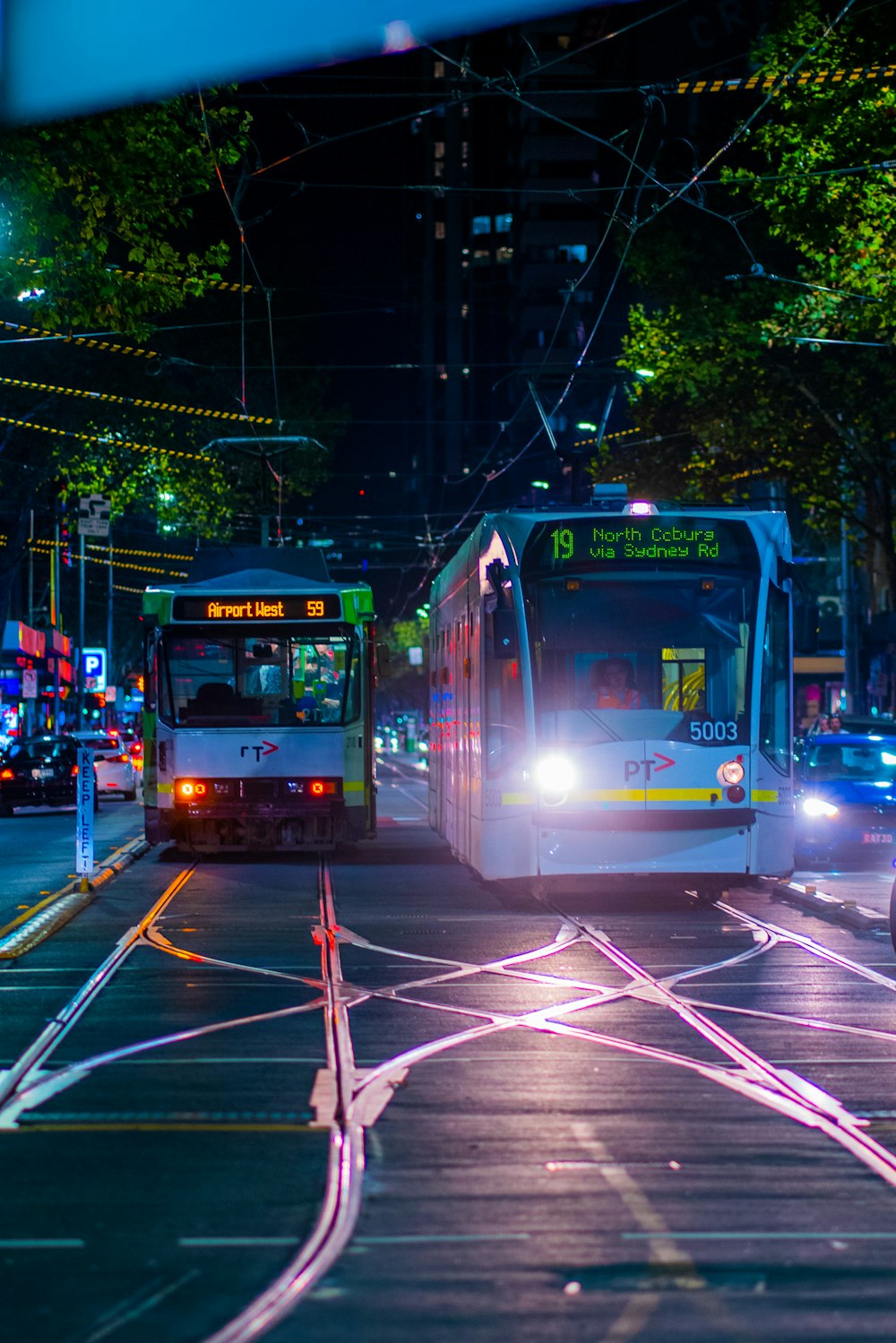 a couple of buses driving down a street at night
