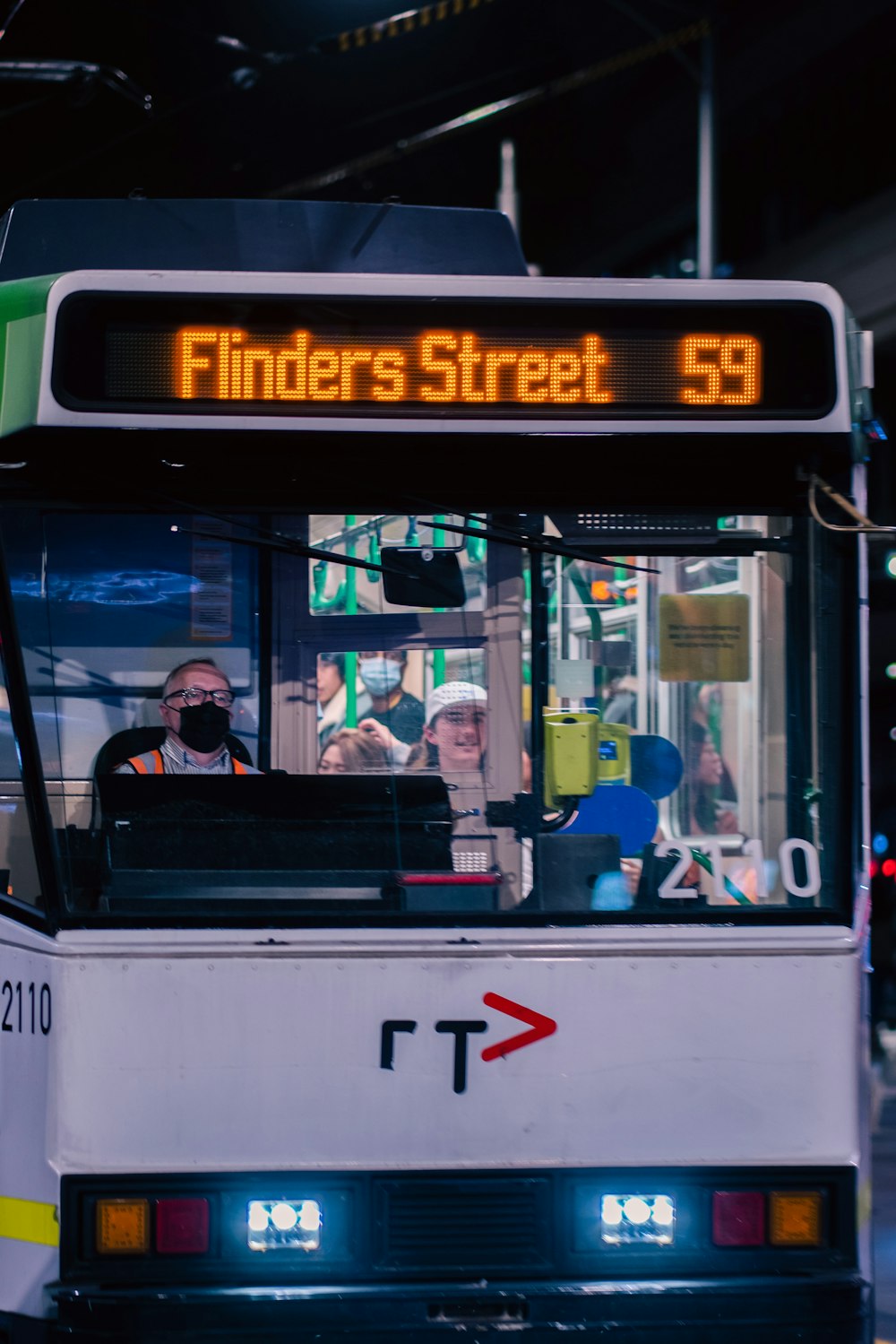 a white bus driving down a street next to a tall building