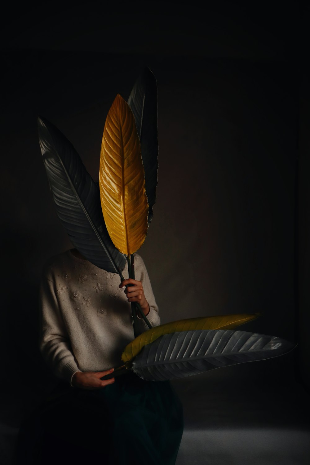 a woman with a feather mask holding a yellow and black feather