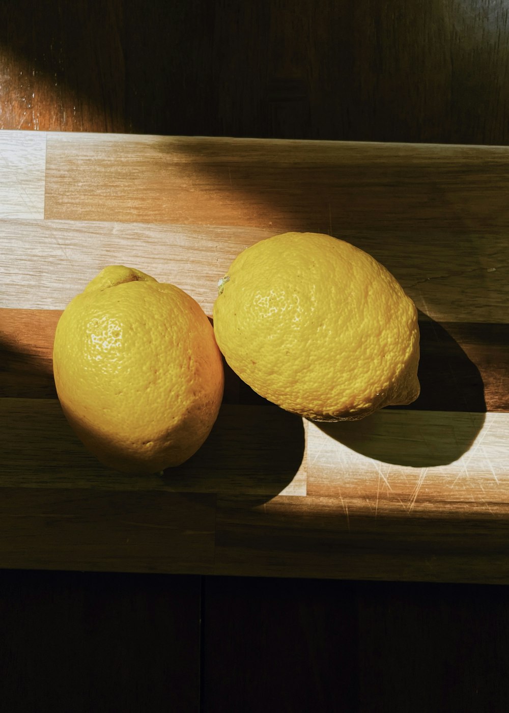 two lemons are sitting on a cutting board