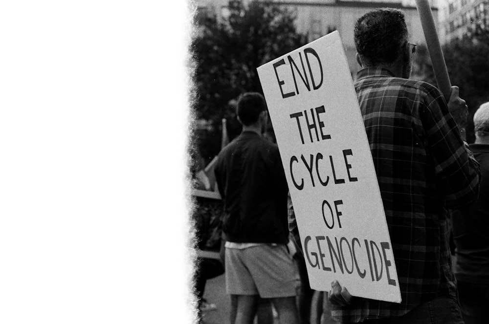 a man holding a sign that says end the cycle of genocode