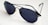 A pair of dark-lensed aviator sunglasses with thin metal frames, resting on a white surface. The lenses are tinted and reflective, with a classic design featuring a double bridge.
