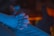 A close-up view of two hands clasped together, illuminated by a blue light. The soft focus and subdued lighting create a sense of calm and introspection.