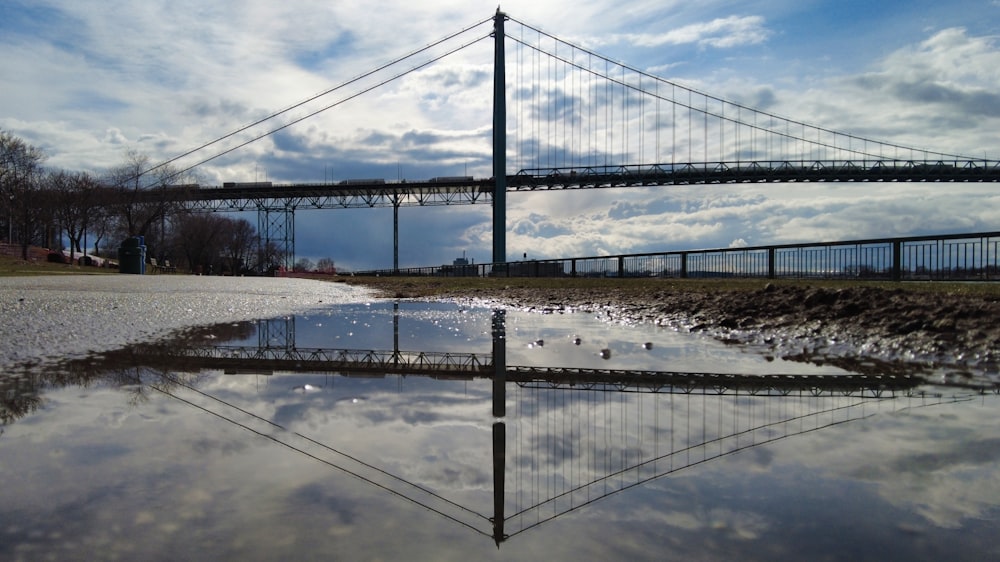 a reflection of a bridge in a body of water