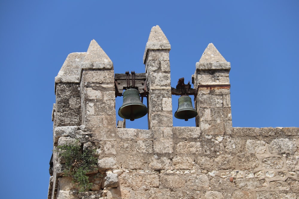 two bells on a stone wall with a blue sky in the background