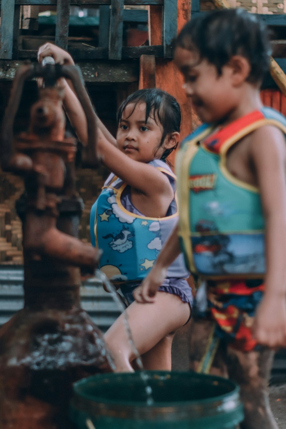 a couple of kids that are standing by a water faucet