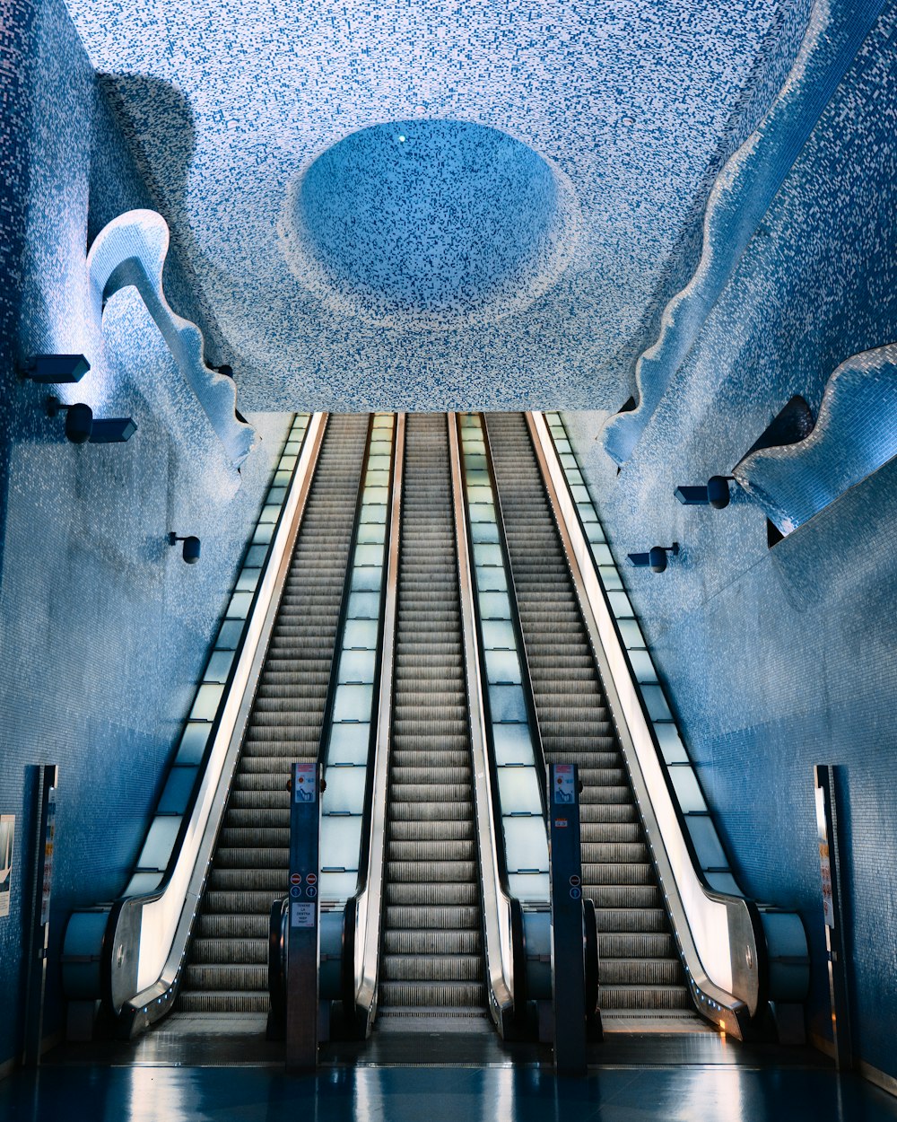 an escalator in a building with a blue ceiling