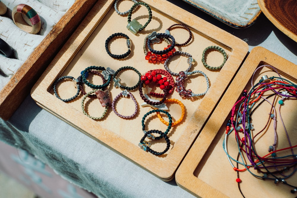 a wooden tray filled with lots of bracelets on top of a table