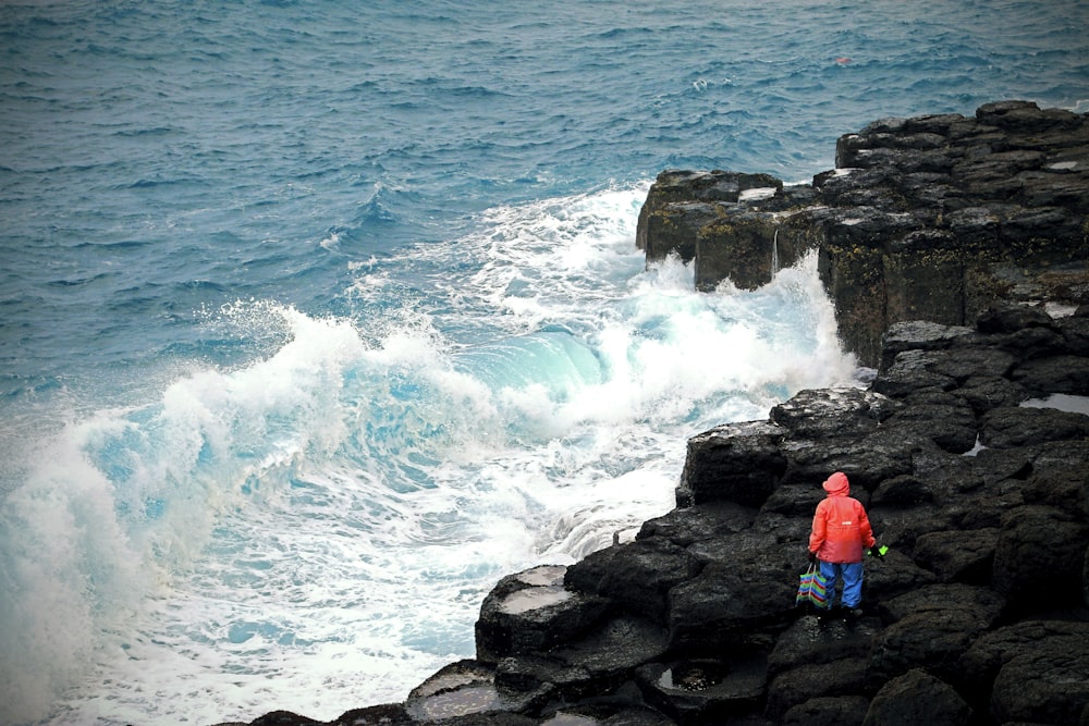 Eine Person, die auf einer felsigen Klippe in der Nähe des Ozeans steht