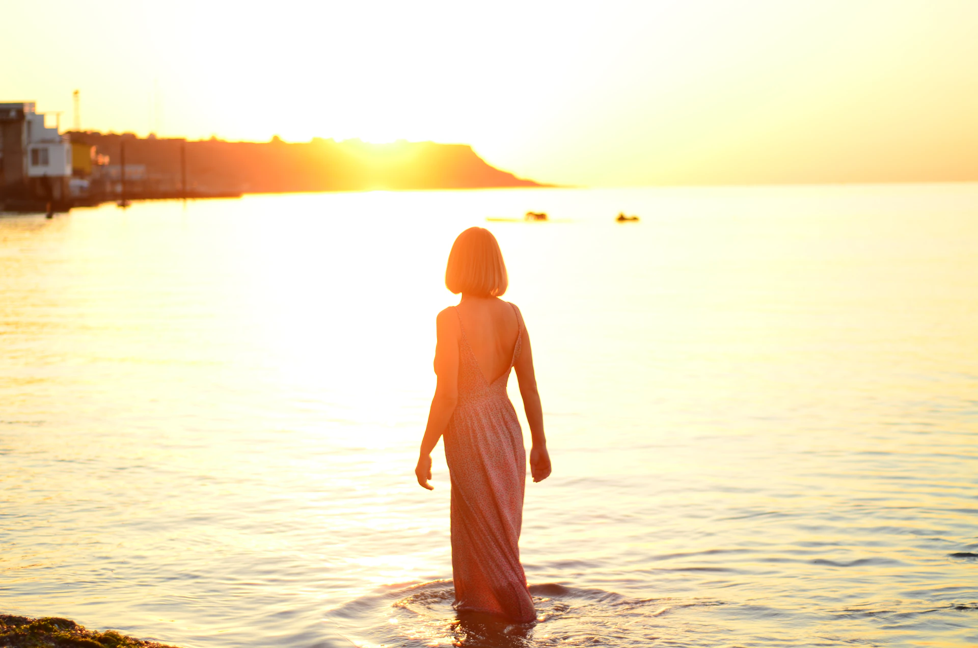 a woman standing in the water at sunset