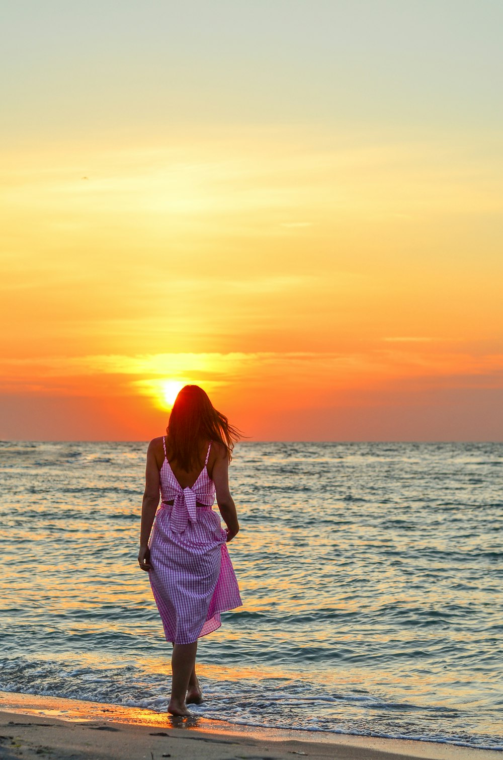 Una mujer caminando por la playa al atardecer