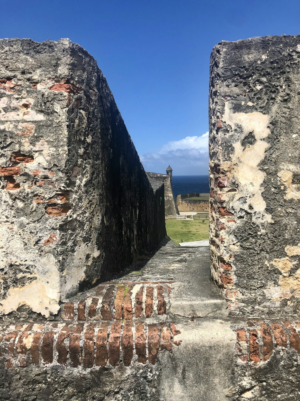 a view of the ocean through two stone walls