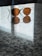 A pair of round, brown-tinted sunglasses rests on a reflective, speckled granite surface. The reflection of the sunglasses is visible on the surface, and there is a soft light coming through the blinds, casting subtle shadows.