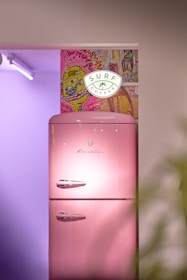 a pink refrigerator sitting in a kitchen next to a potted plant