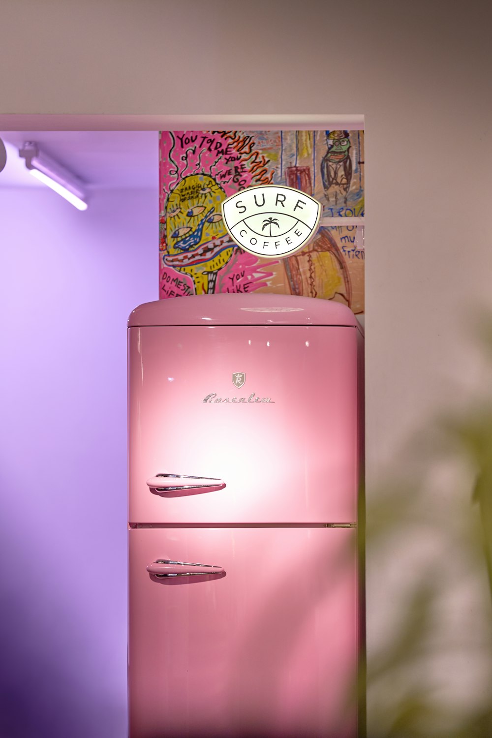 a pink refrigerator sitting in a kitchen next to a potted plant