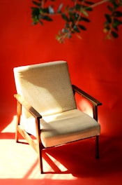 A cozy vintage wooden armchair with a patterned cushion in a sunlit room.