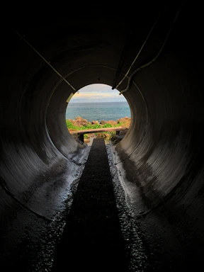 a dark tunnel with a view of the ocean