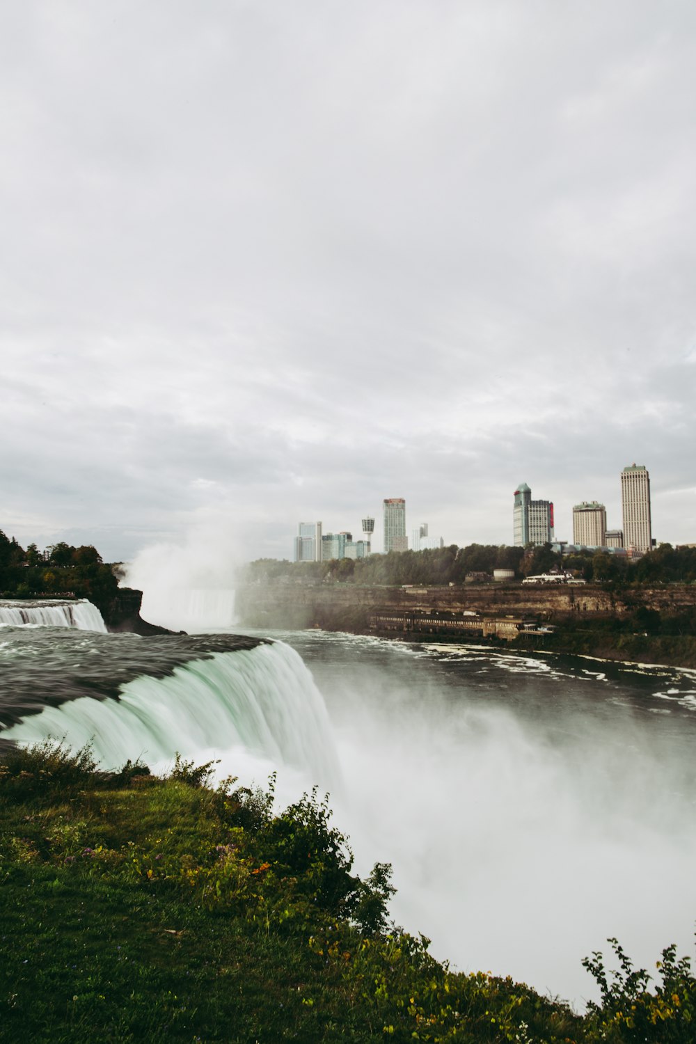 a large waterfall with a city in the background