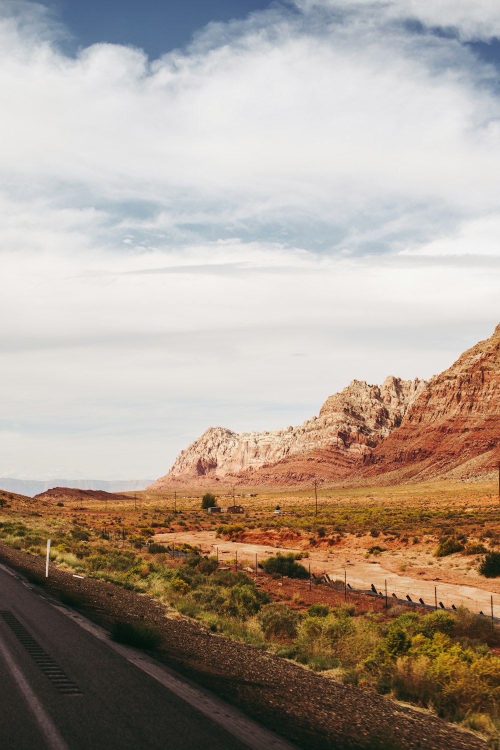 a road in the middle of a desert with a mountain in the background