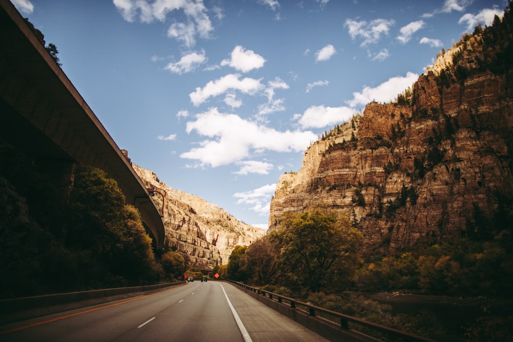 a car driving down a road next to a mountain