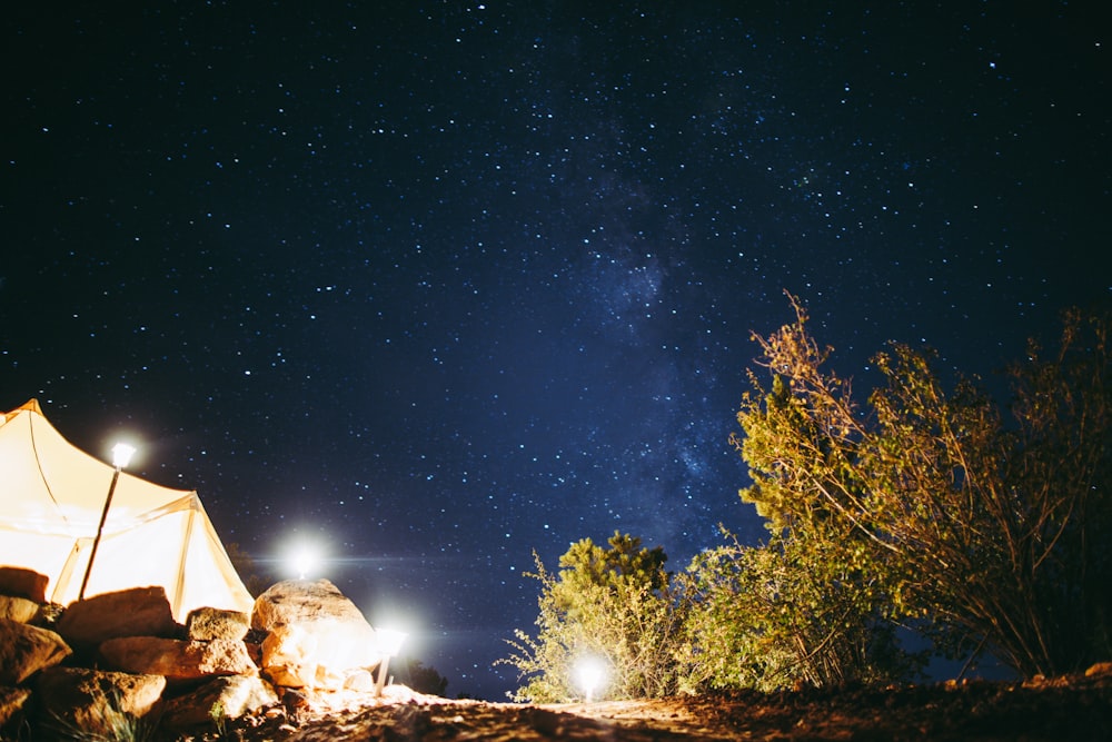 a tent is lit up at night under the stars