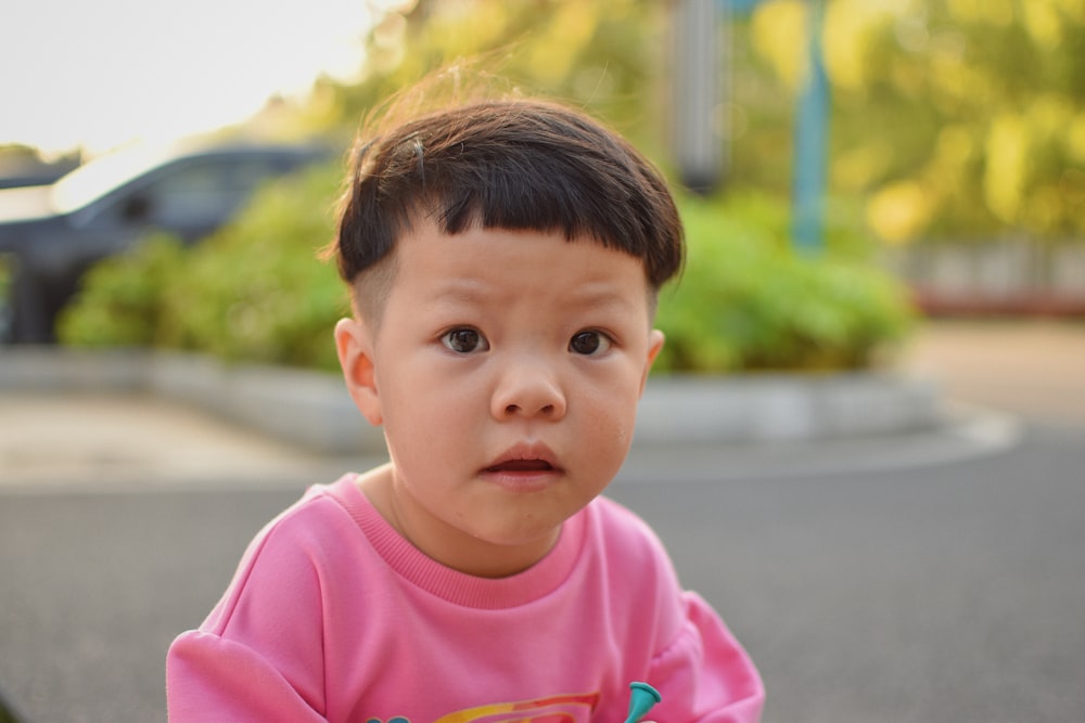 a little boy sitting on a skateboard in the street