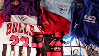 a pile of sports jerseys sitting on top of a bed