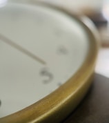 A close-up of a ticking clock with blurred background showing hands ready to act.