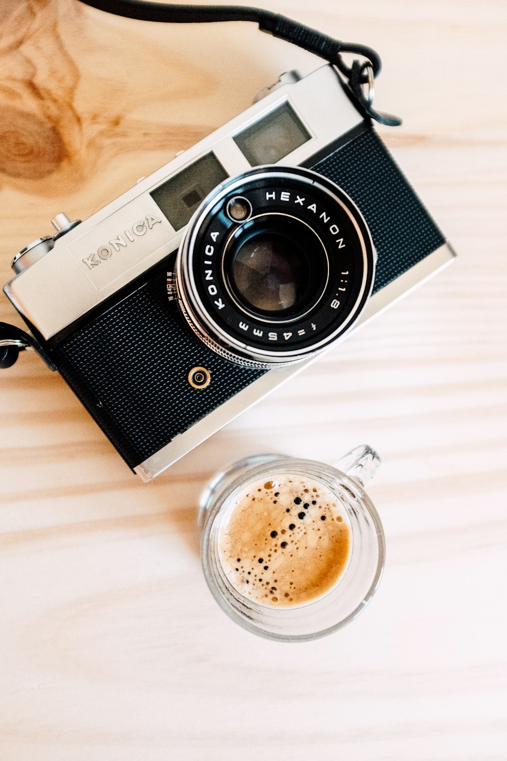 a camera sitting on top of a wooden table next to a cup of coffee