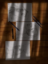 Close-up of detailed graphite and colored pencil drawings with black, white, and blue tones.