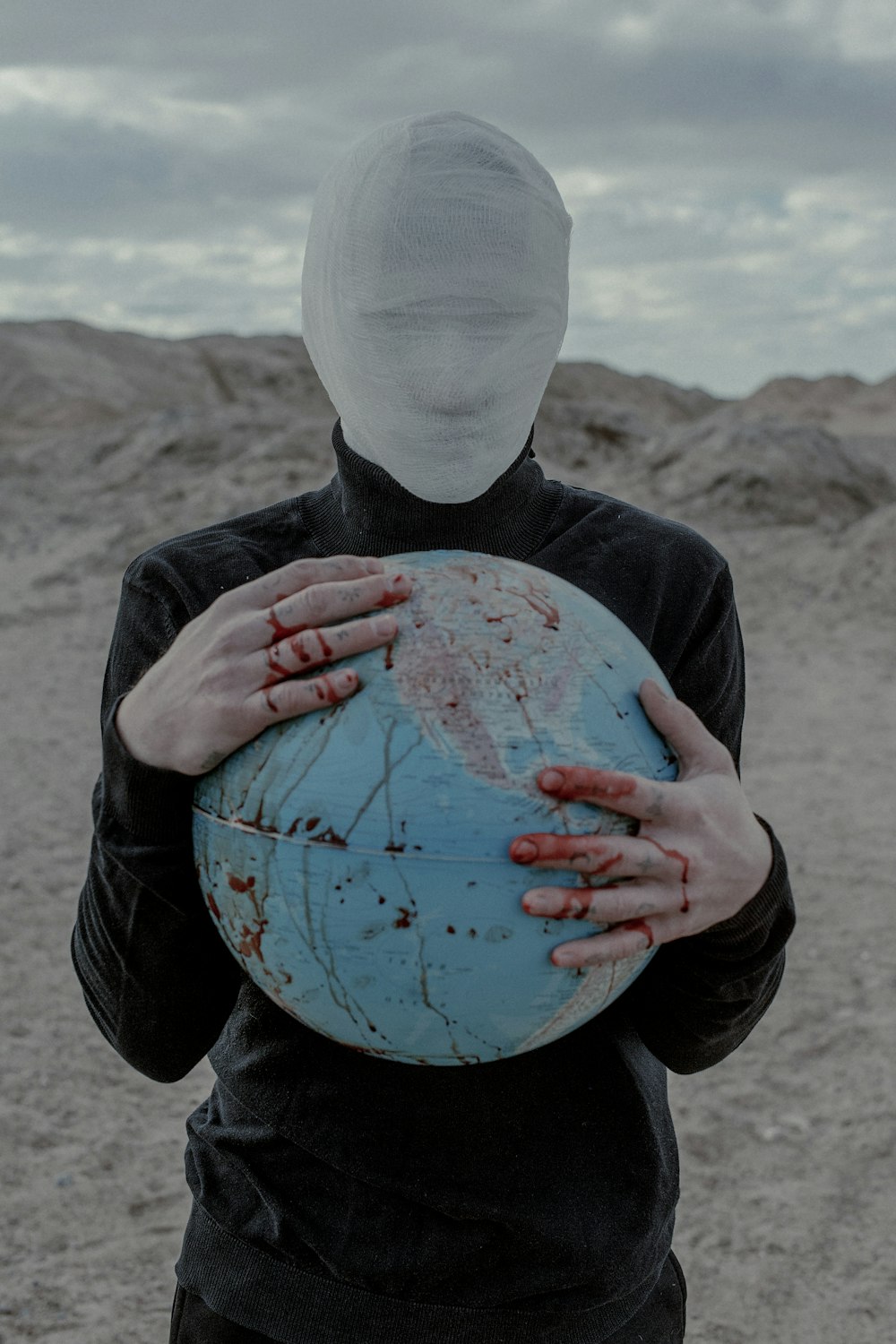 a person in a white mask holding a globe