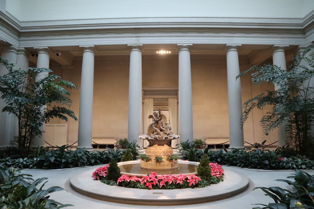 a fountain surrounded by plants and flowers in a building