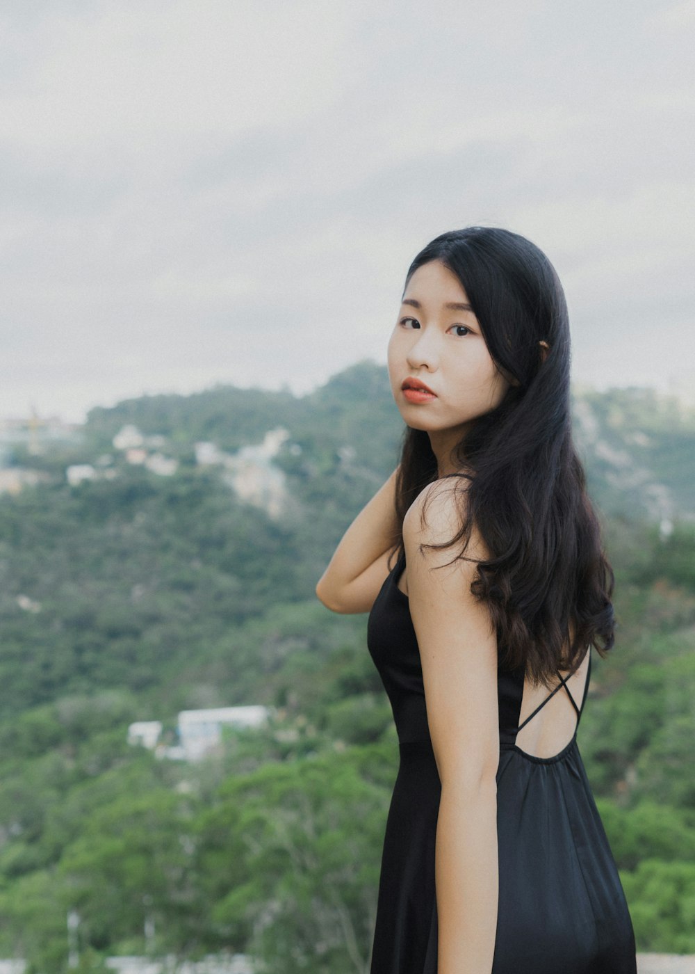 a woman in a black dress standing on top of a hill