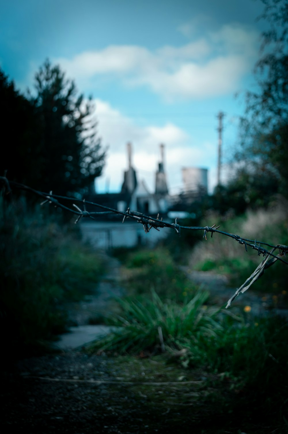 a barbed wire fence with a factory in the background