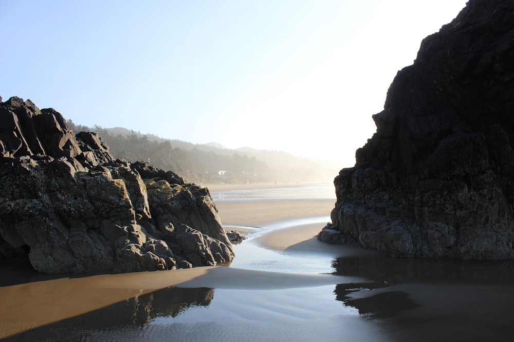 a sandy beach next to a rocky cliff