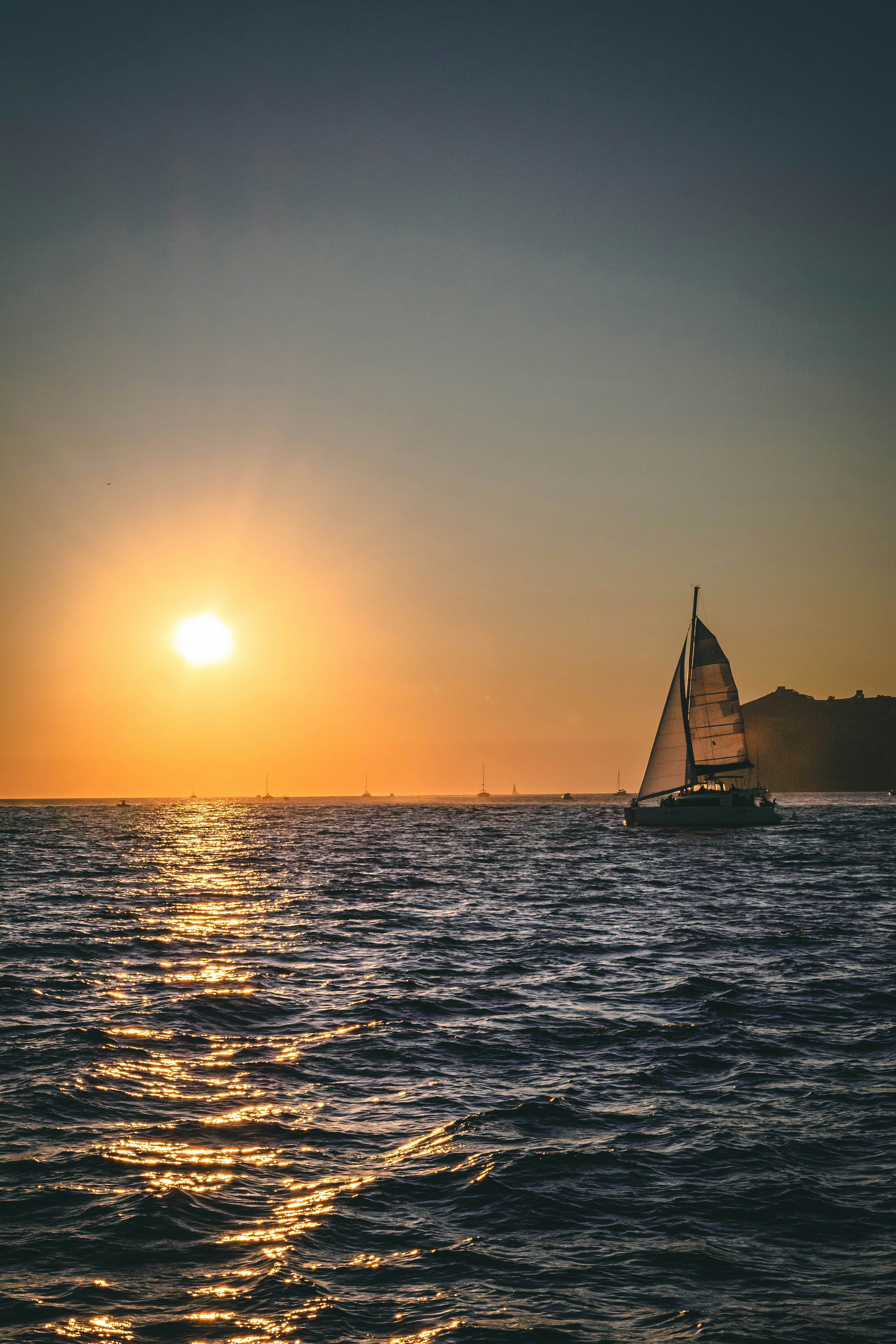 a sailboat in the ocean at sunset