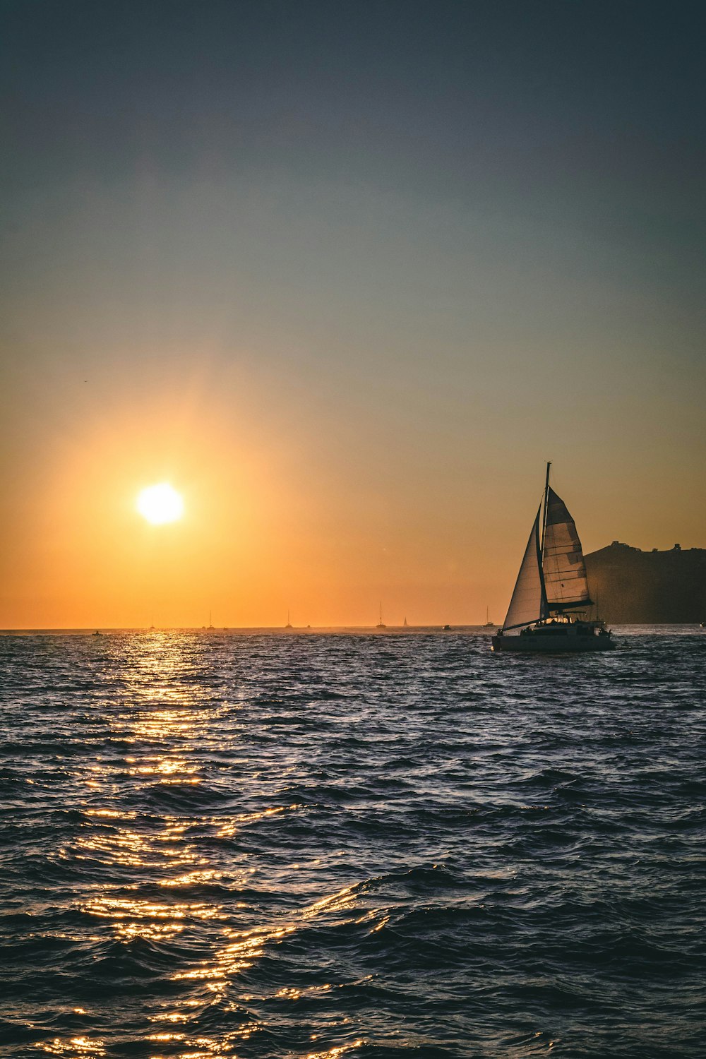 a sailboat in the ocean at sunset