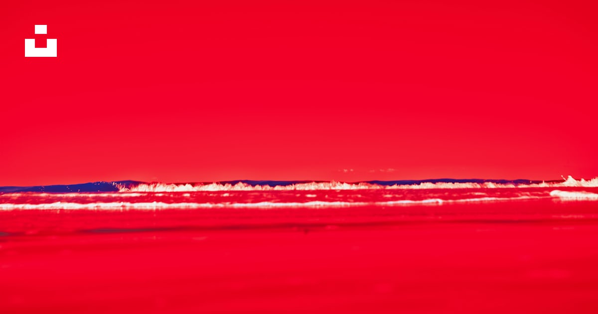 Une photo rouge d’une plage avec un bateau dans l’eau photo – Image ...