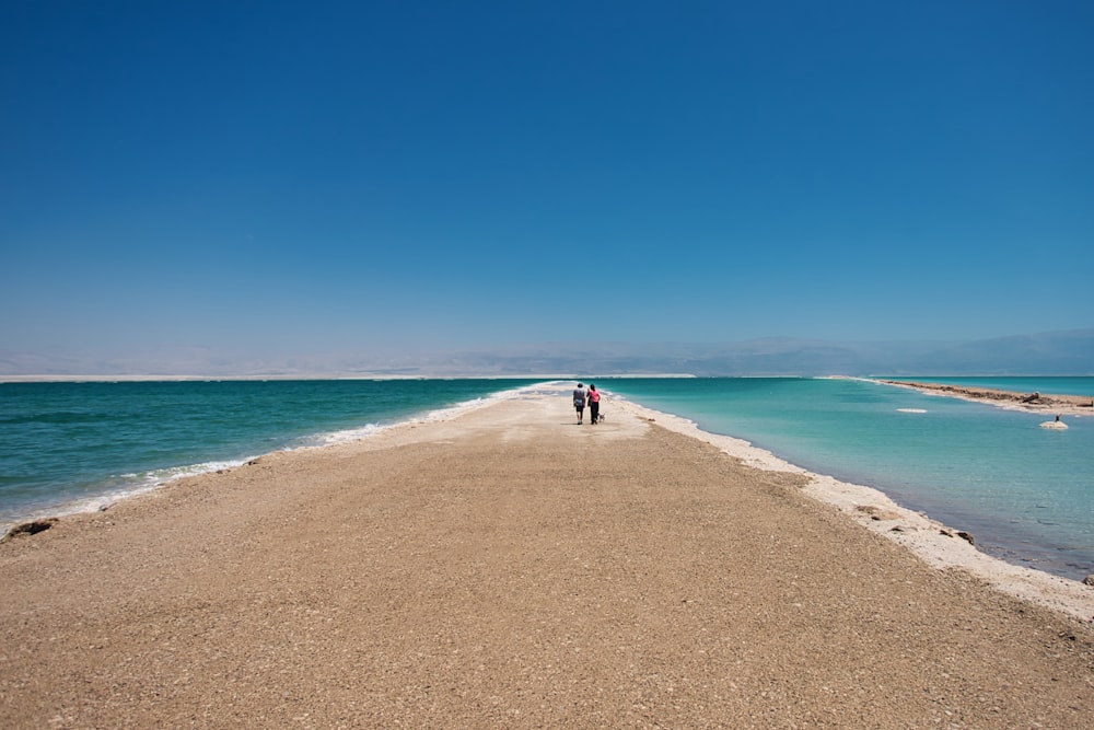 two people standing on a beach next to the ocean