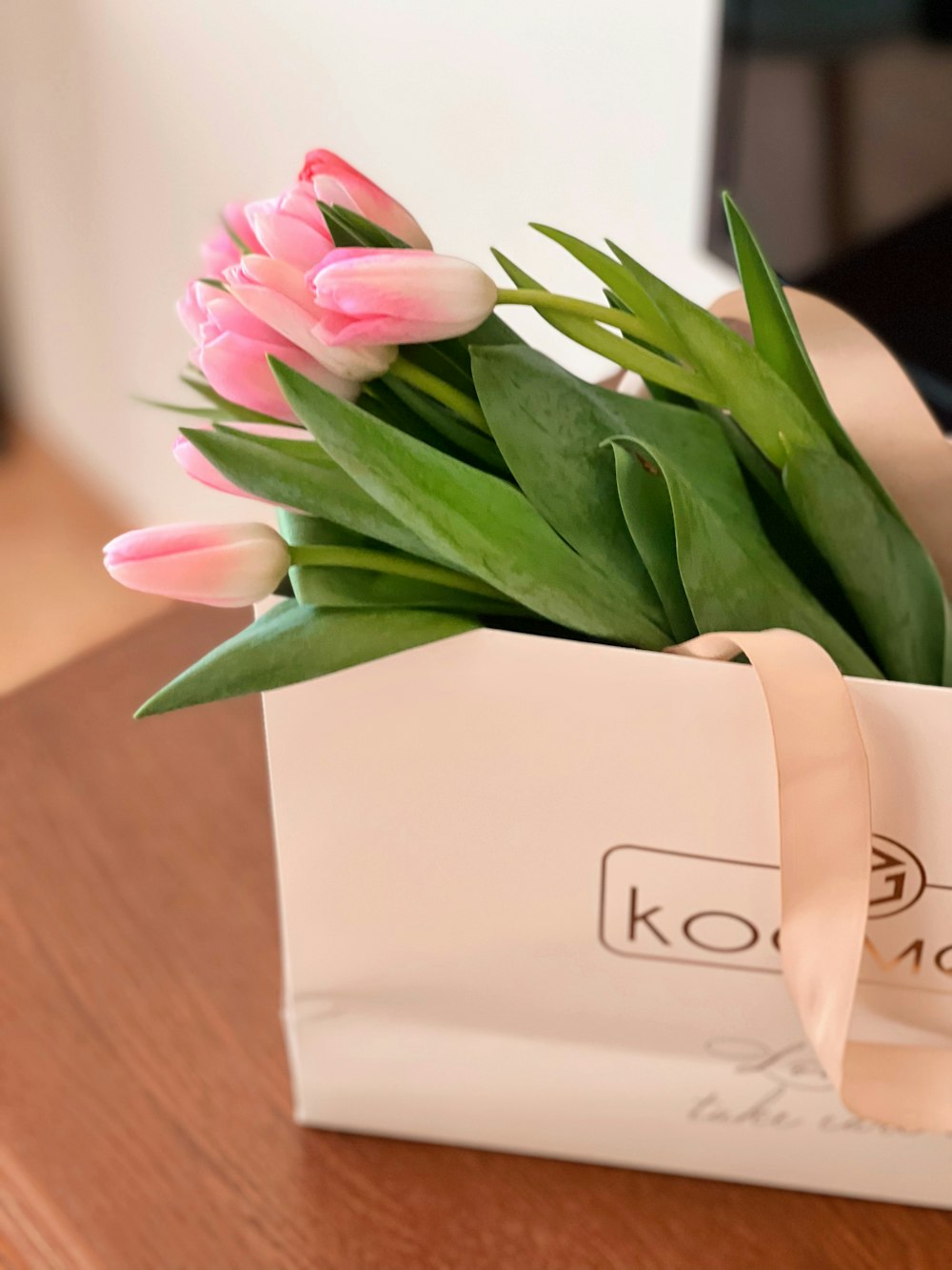 a bouquet of pink tulips in a paper bag